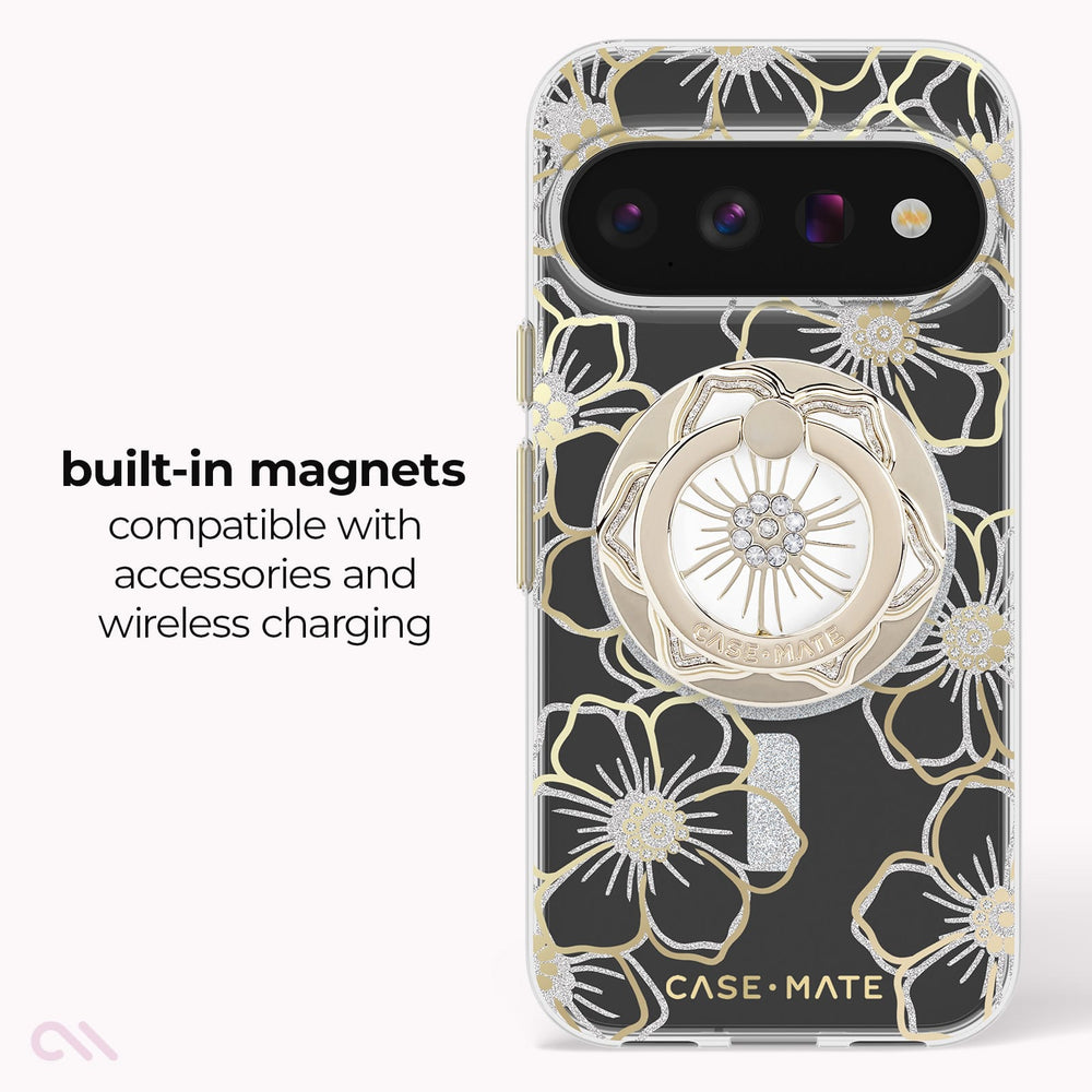 A clear phone case with a black floral pattern outlined in gold, featuring a built-in circular magnetic kickstand and a silver flash cutout. Text on the left reads 'built-in magnets compatible with accessories and wireless charging'.