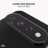 A close-up of a black smartphone showing the rear camera area with a clear protective overlay around the lenses. Text at the top reads 'crystal clear pictures day and night' on a light gray background.