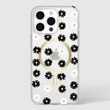 Clear iPhone 15 Pro Max case with black and white daisy pattern, gold MagSafe ring, and small rhinestone accents throughout.