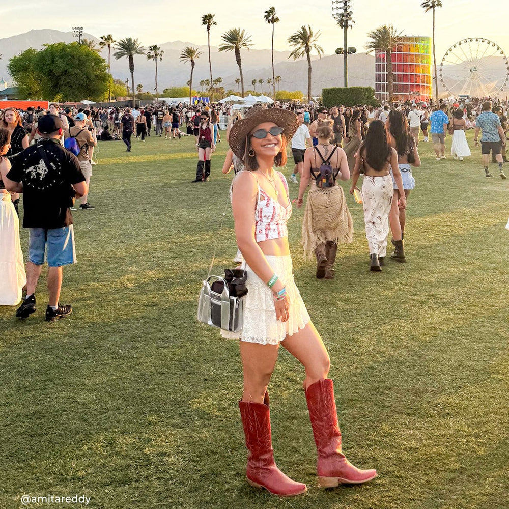 Woman in cowboy boots and a hat at a music festival with palm trees and a Ferris wheel in the background. #color_silver chrome