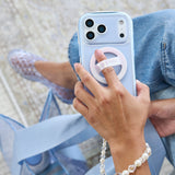 A close-up lifestyle shot of a person holding a light blue phone case with a built-in ring stand. The person is wearing blue jeans, clear lace-up flats, and a pearl bracelet, with a matching light blue bag in the background.
#color_jelly pop carolina blue
