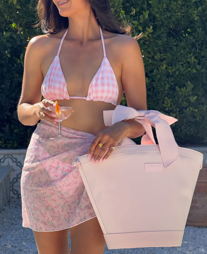 Woman in a pink checkered bikini top and skirt holding a Ballet Pink Cooler outdoors.
#color_ballet pink bow