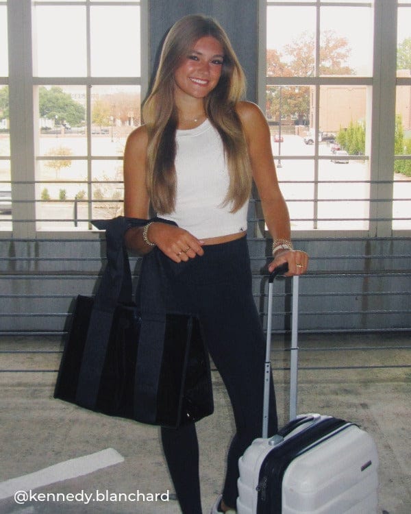 Girl standing in parking garage with carry on and Midnight Black Bow Jelly Tote Bag