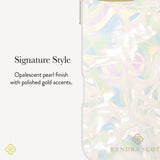 A close-up of a phone case with an iridescent, opalescent pearl finish and subtle gold accents, shown next to descriptive text that reads 'Signature Style' and 'Opalescent pearl finish with polished gold accents.' The brand name 'KENDRA SCOT' is visible at the bottom.