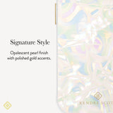 A close-up of a phone case with iridescent pearl-like patterning and small gold accents, shown beside text reading 'Signature Style' and 'Opalescent pearl finish with polished gold accents.' The Kendra Scott logo appears near the bottom right of the case.