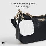 Black handbag with a white airpods case attached using a gold ring clip, on a light gray background.