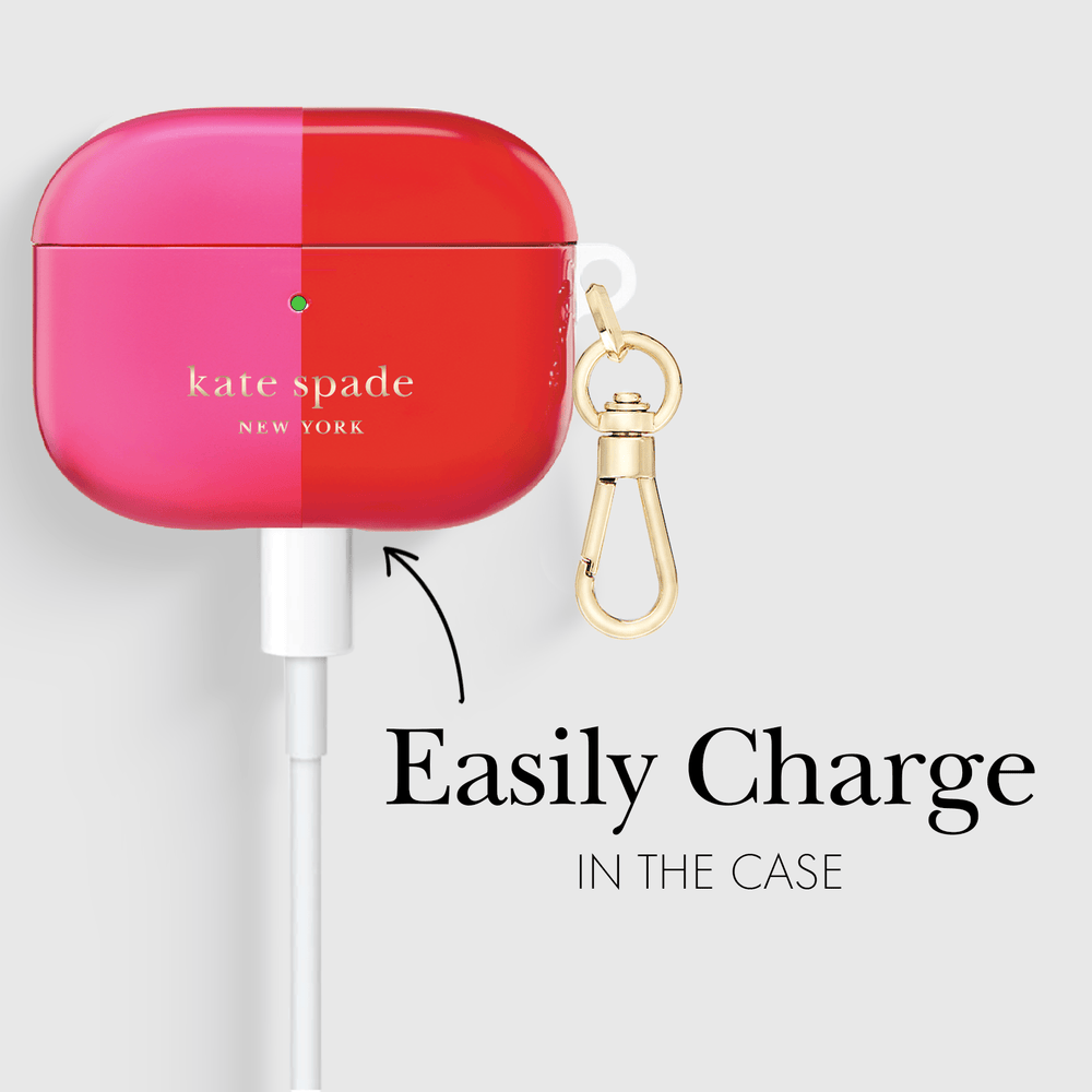Kate Spade Airplane Case in a vibrant pink and red split design, shown with a white charging cable plugged in and a gold carabiner clip. Text on the image reads 'Easily Charge IN THE CASE'.