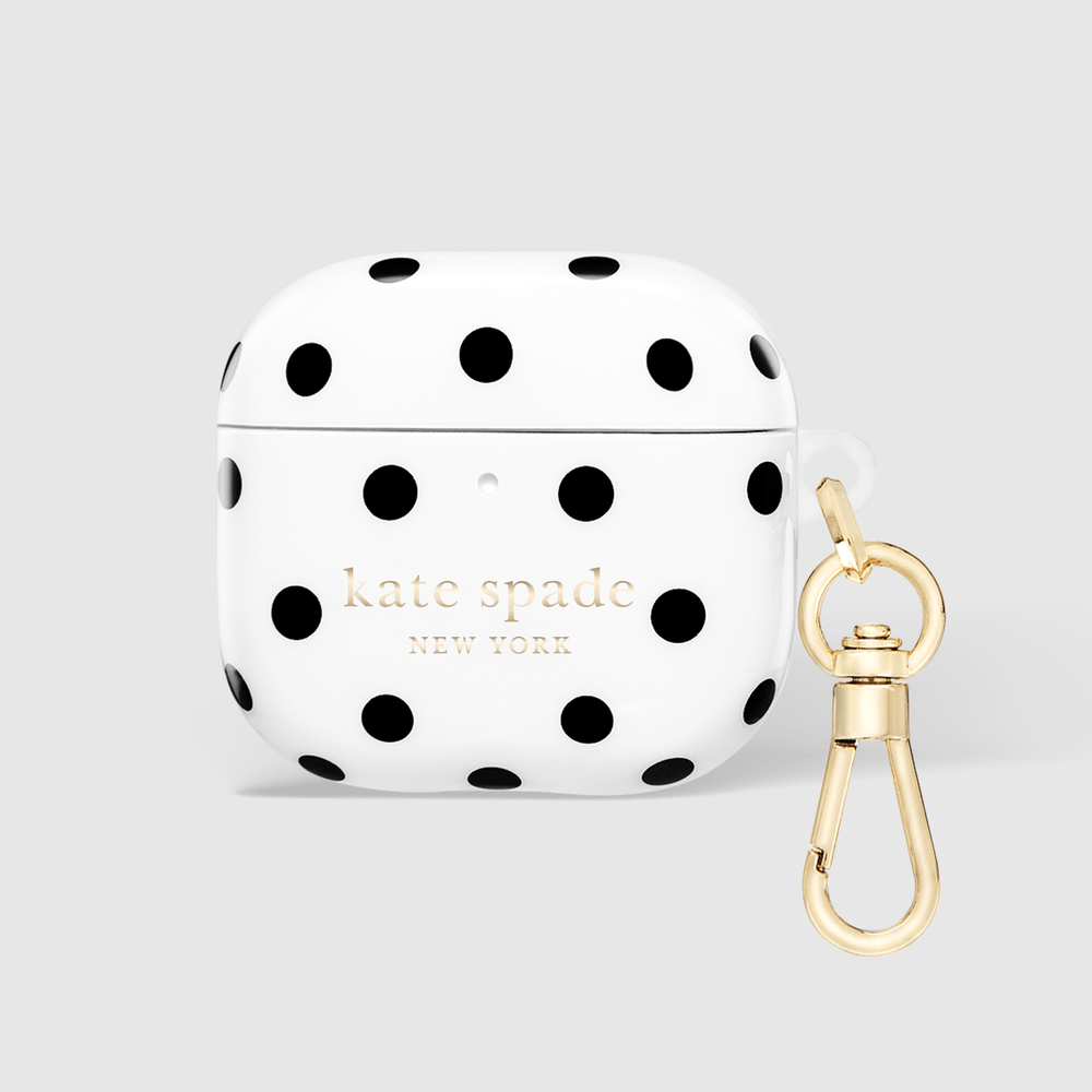 White AirPods case with black polka dots and gold 'kate spade NEW YORK' lettering, shown with a gold carabiner clip on a light gray background.