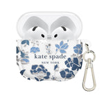 A clear protective case for an AirPods charging case, featuring a blue and white floral pattern and the 'kate spade NEW YORK' logo. The case is shown with the AirPods inside and a silver carabiner clip attached on a plain white background.
