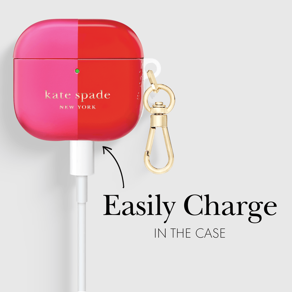 Kate Spade New York AirPods case in a vibrant pink and red gradient finish, featuring a gold-tone carabiner clip and a white charging cable inserted, with text reading 'Easily Charge IN THE CASE' on a light gray background.