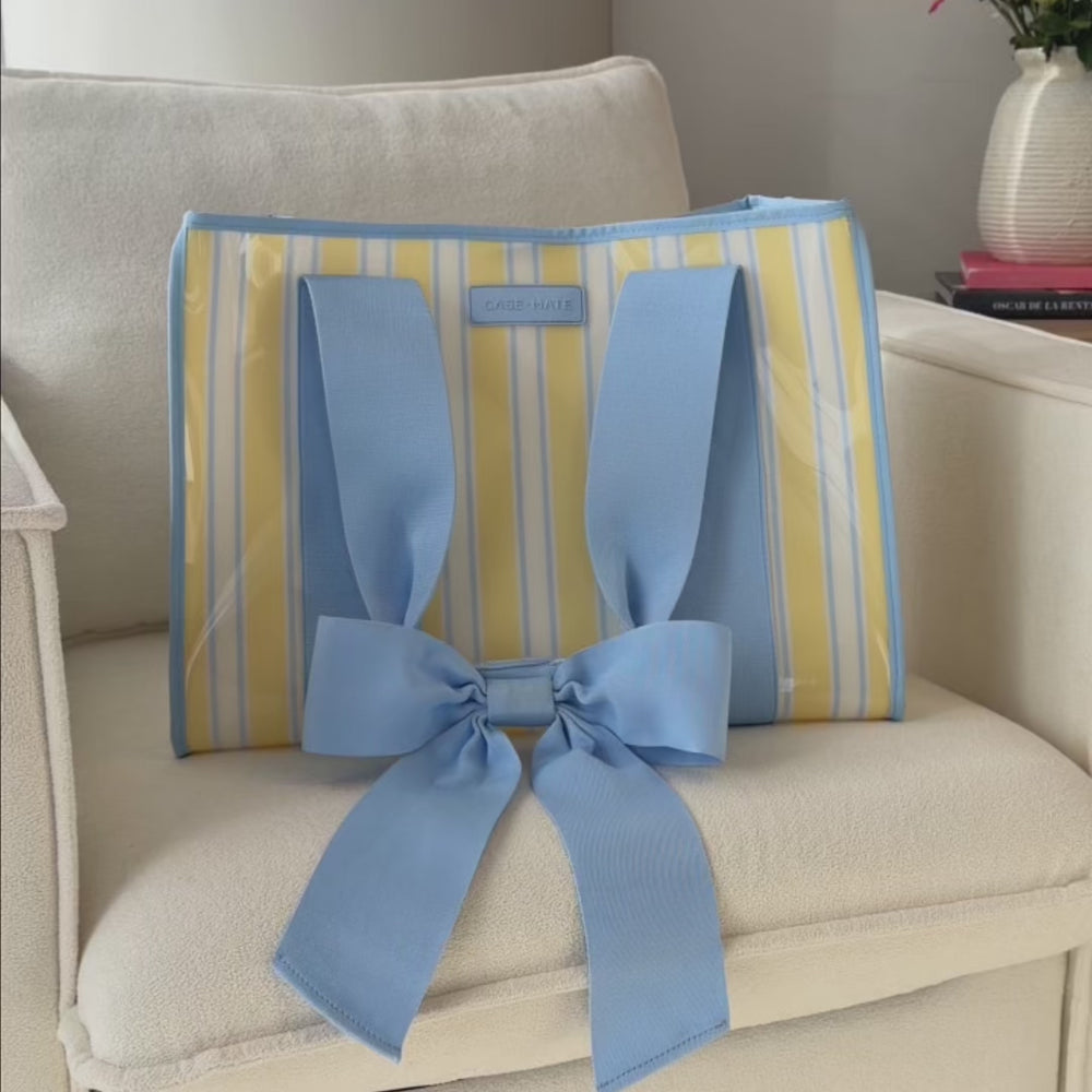 Detail and close up shot of the Cabana stripe bow jelly tote bag placed on a cream accent chair