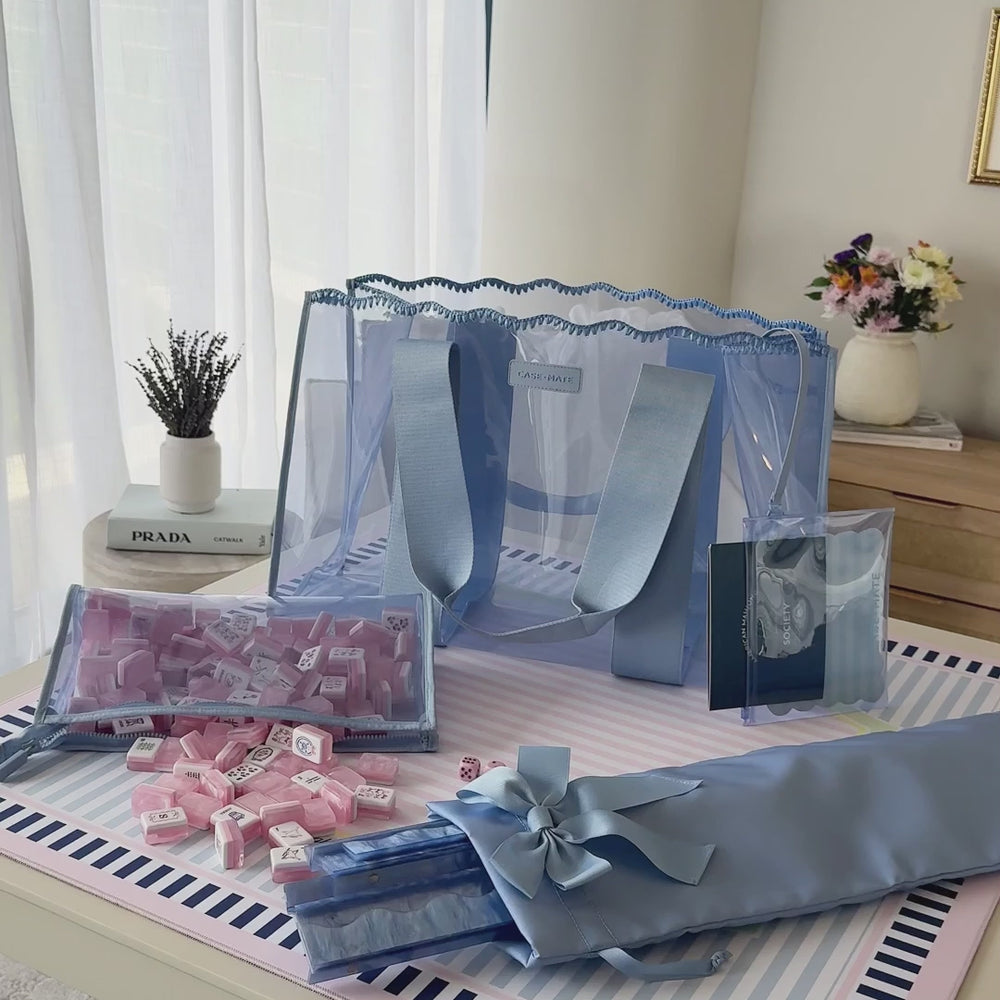 Woman packing her mahjong tote with all the playing accessories like tiles, racks, and mats. 

#color_carolina blue crochet wave