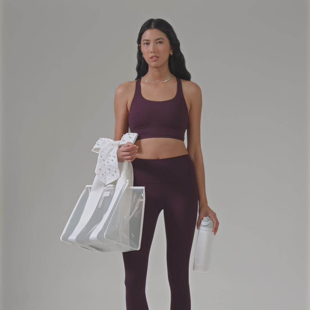 A woman showcasing her Ivory Pearl Bow Jelly Tote with the size of a waterbottle
#color_ivory pearl bow