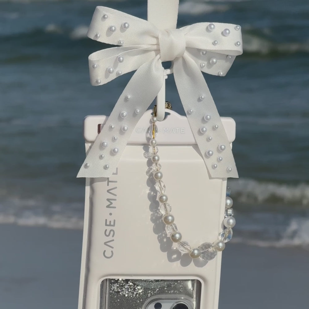 A video showing the waterproof floating pouch in action on the beach #color_ivory pearl bow