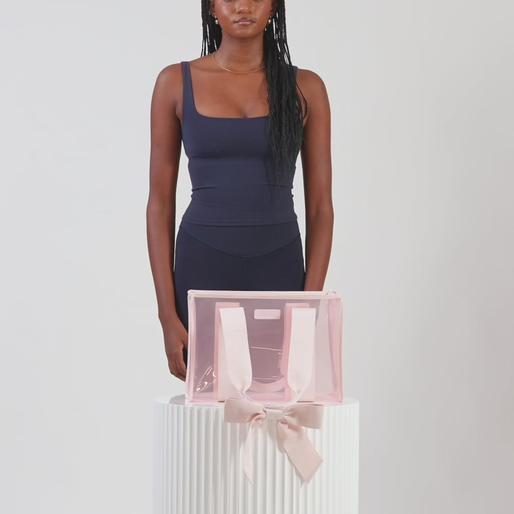 A woman showing off her medium jelly tote
#color_ballet pink bow