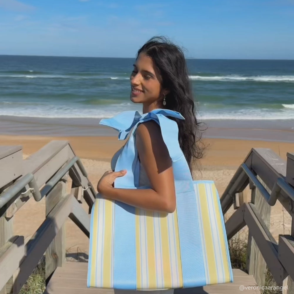A woman showing off her Cabana Stripe Jelly tote bag on the beach 
#color_cabana stripe bow