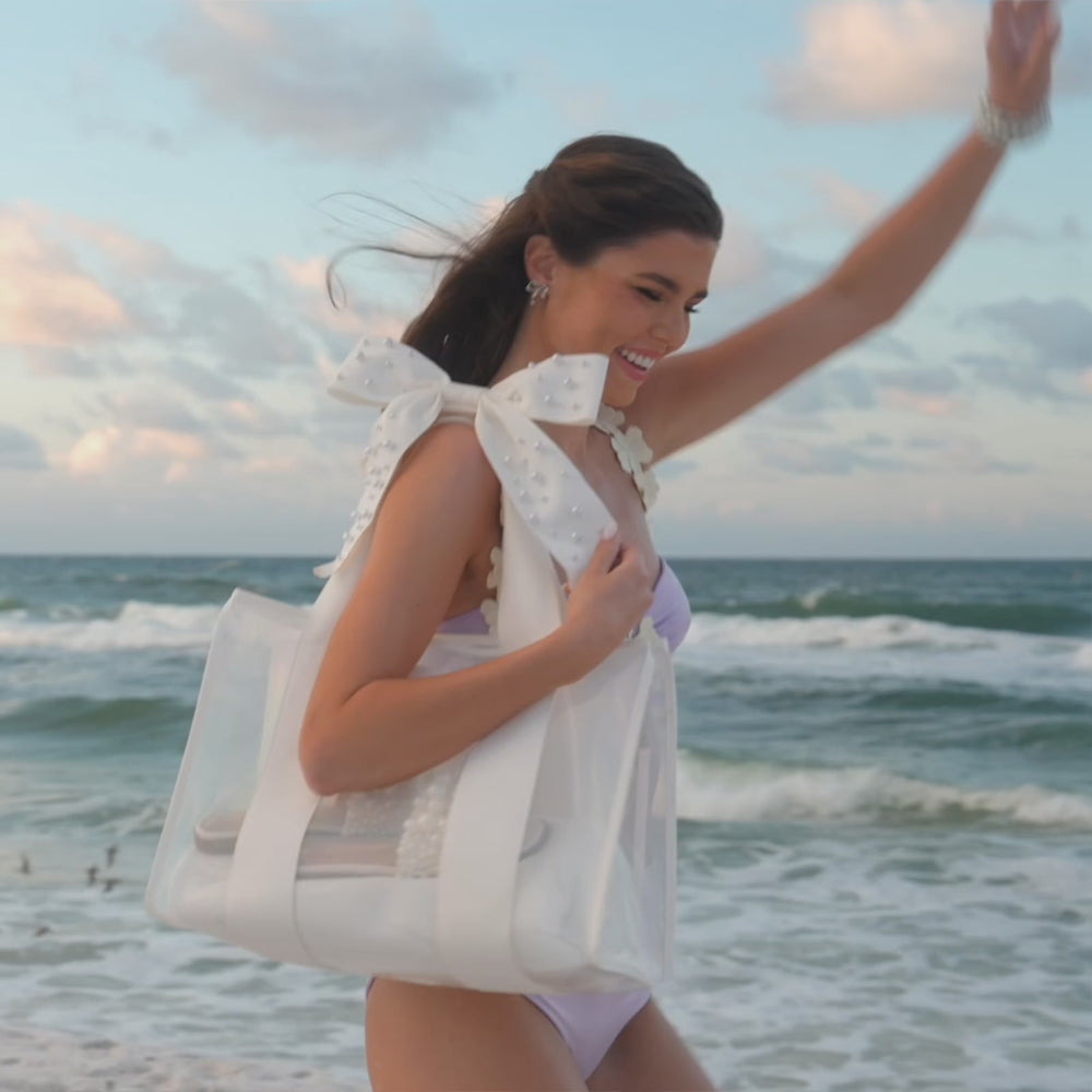 Woman showcasing the Ivory Pearl Jelly Tote on the beach showing it as a beach bag
#color_ivory pearl bow