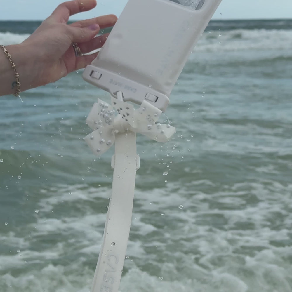 A woman on the beach shore showing how to use a waterproof floating pouch