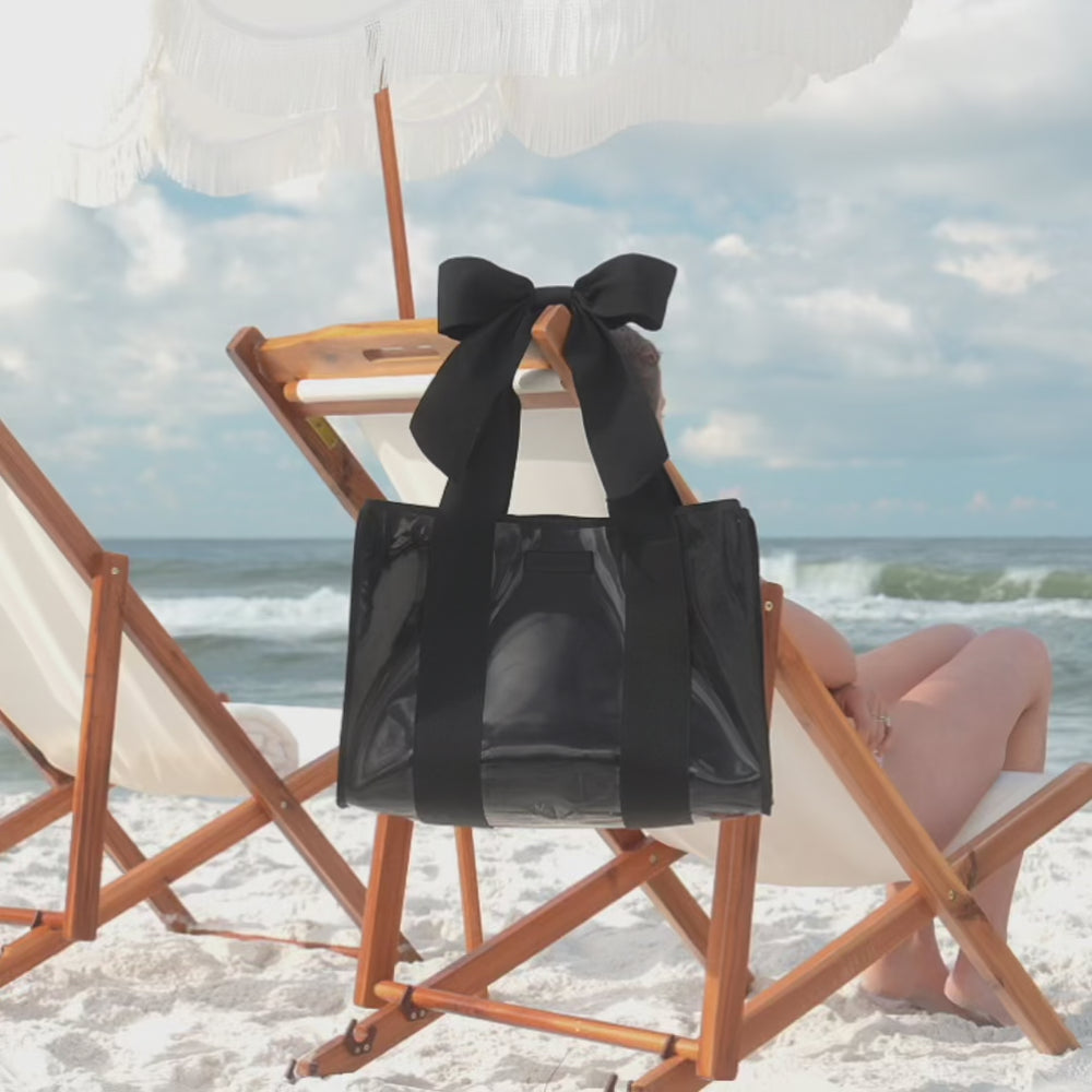 A midnight black bow jelly tote on the beach being shown off as a beach bag
#color_midnight black bow