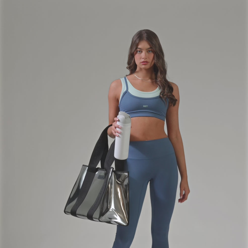 A woman showing off here Silver Chrome Jelly Tote with a water bottle to show size
#color_silver chrome