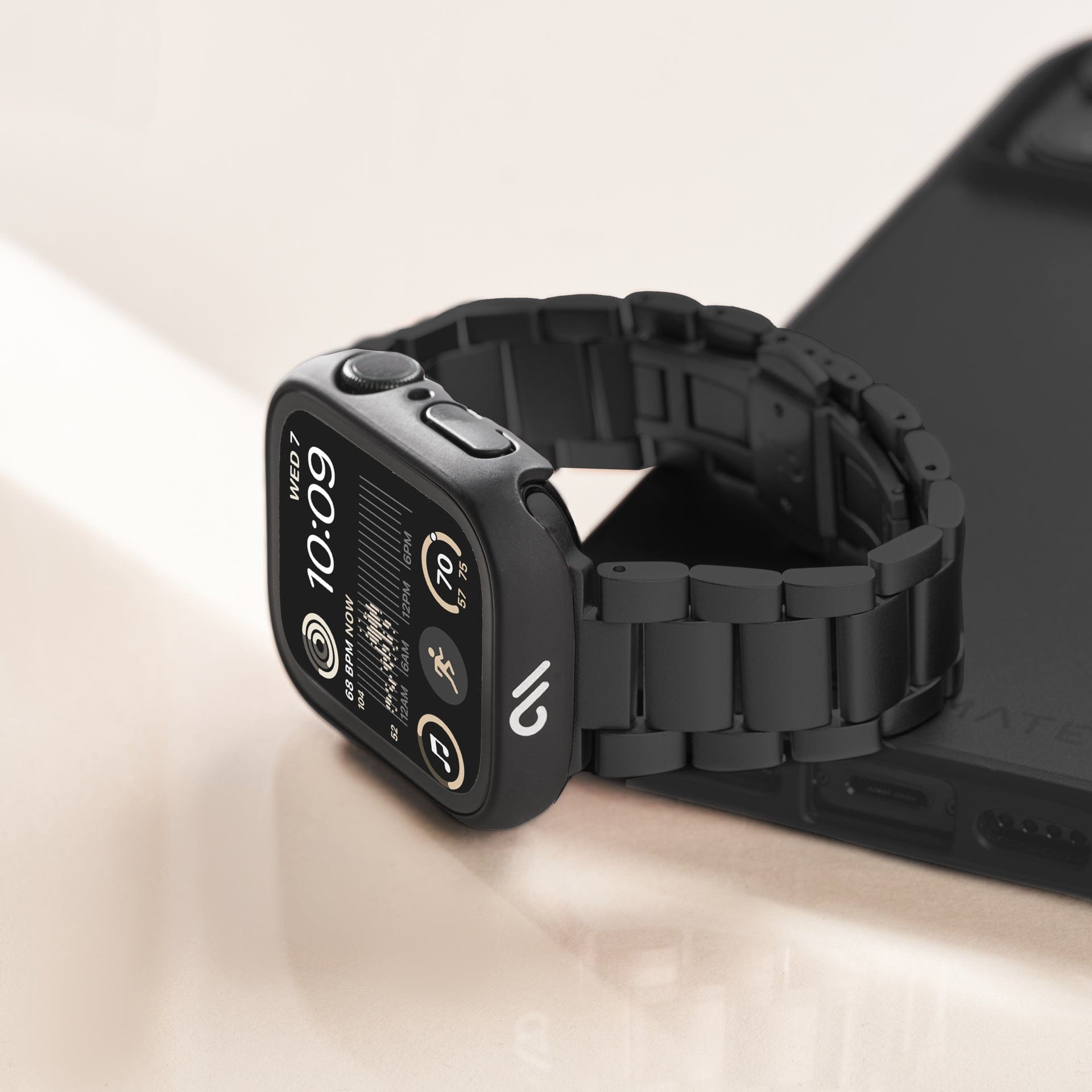 Apple Watch with tough black case and black link chain sitting on top of a phone. 