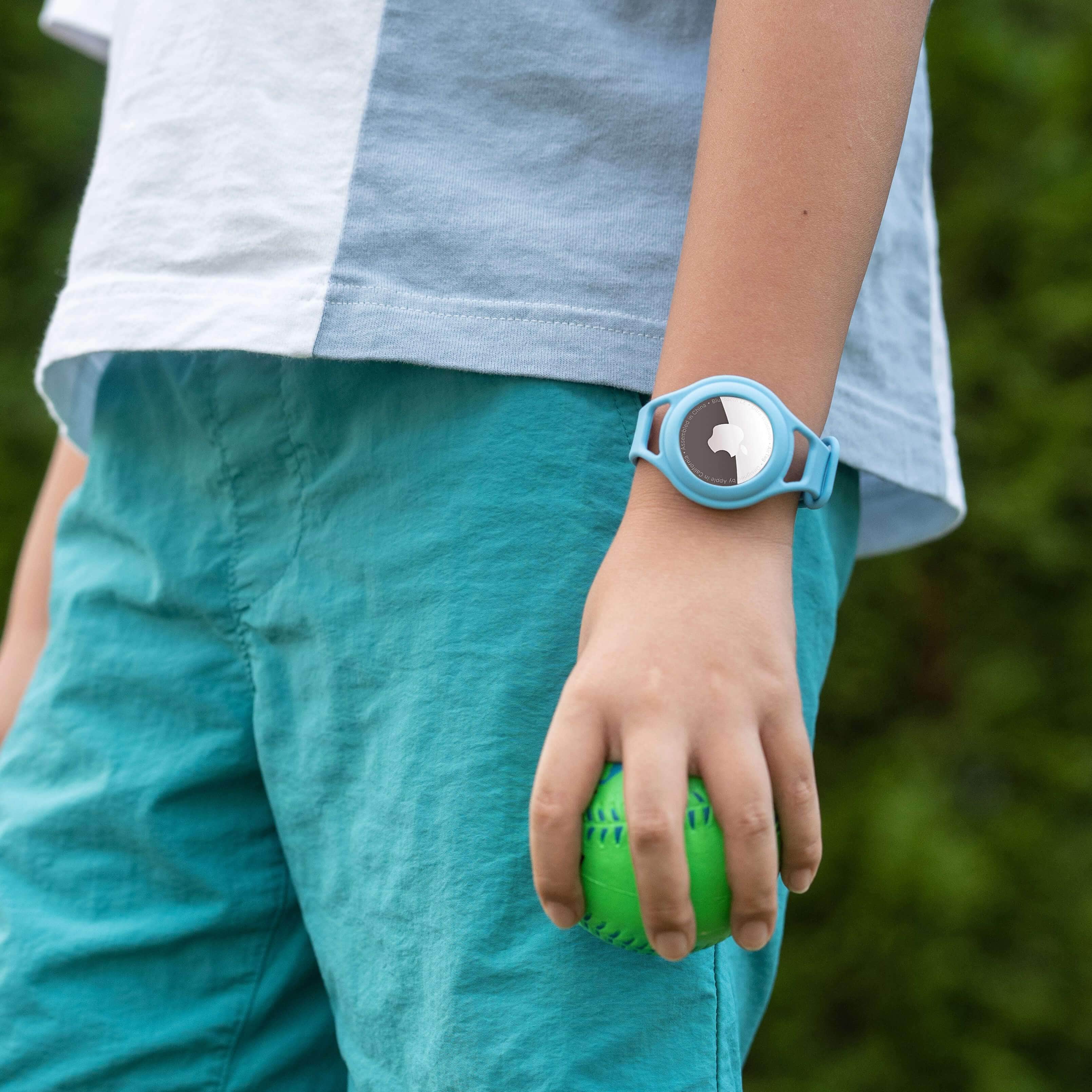 Kid holding ball in hand with tracker bracelet on wrist. color::Blue