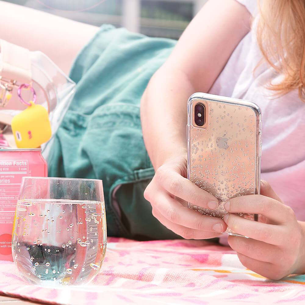 Woman typing on phone in tough fizz case. color::Sparkling Water